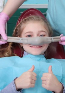 a child patient giving thumbs up with nitrous oxide